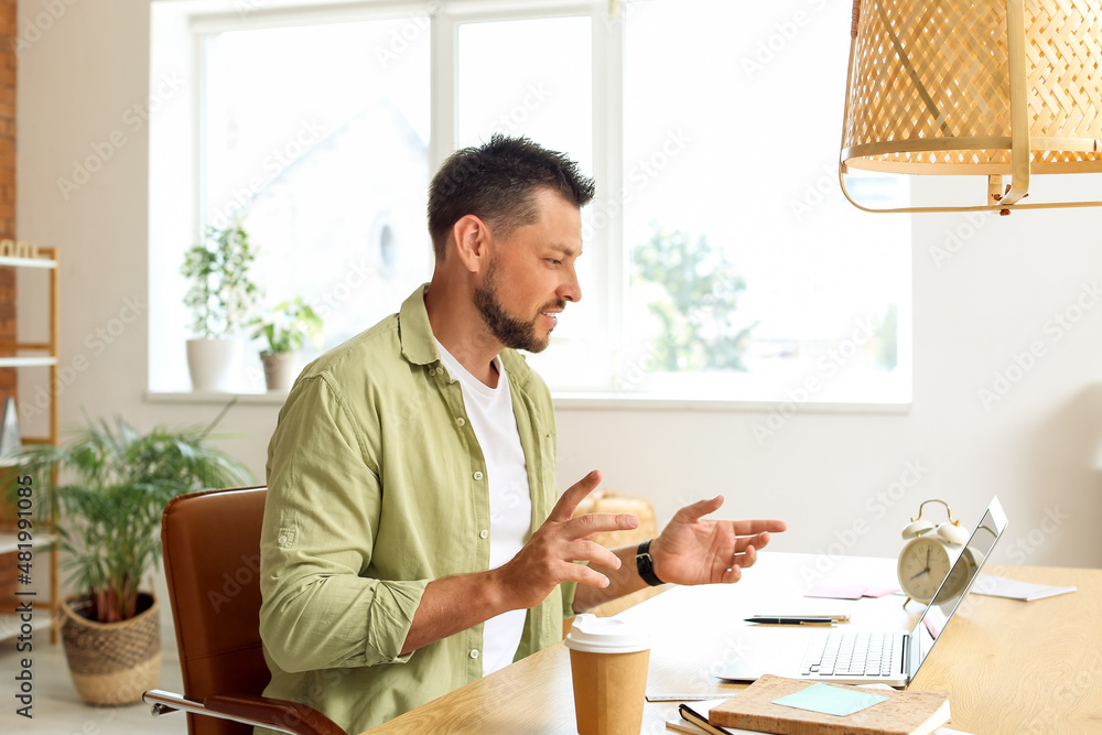 Handsome man working with laptop at table in office