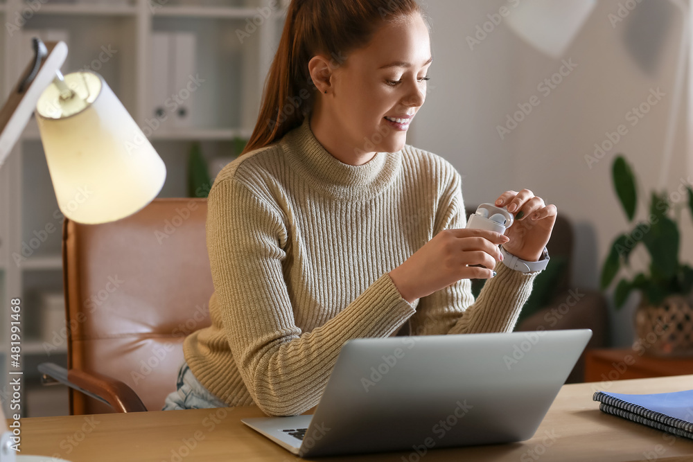 年轻女子晚上拿着笔记本电脑在家听音乐