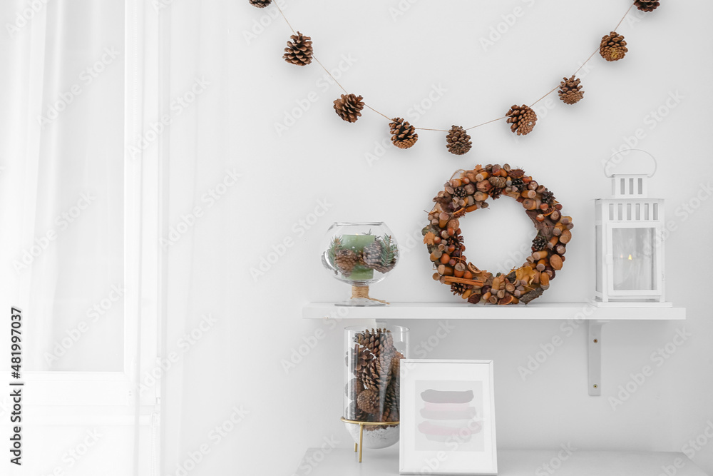 Pine cones, natural wreath and candles on table in room