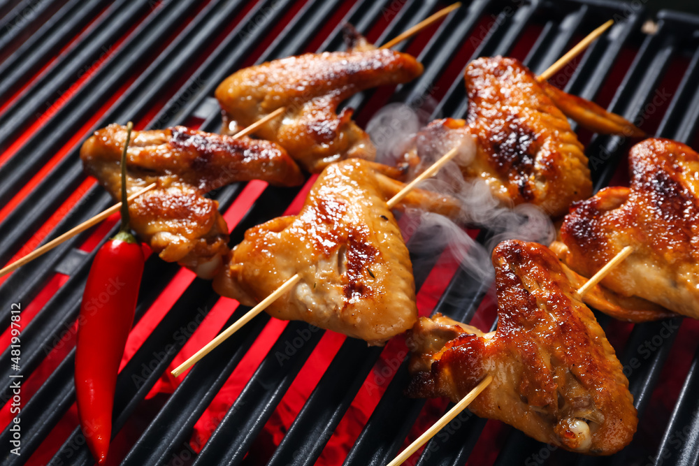 Tasty chicken wings skewers on grill