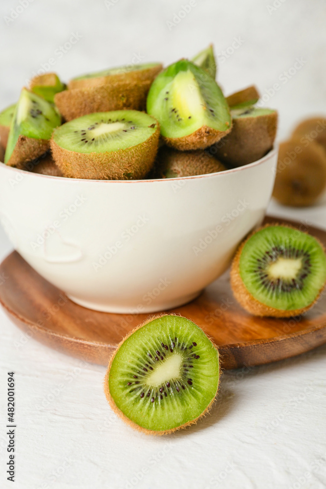 Bowl with fresh cut kiwi on light background, closeup