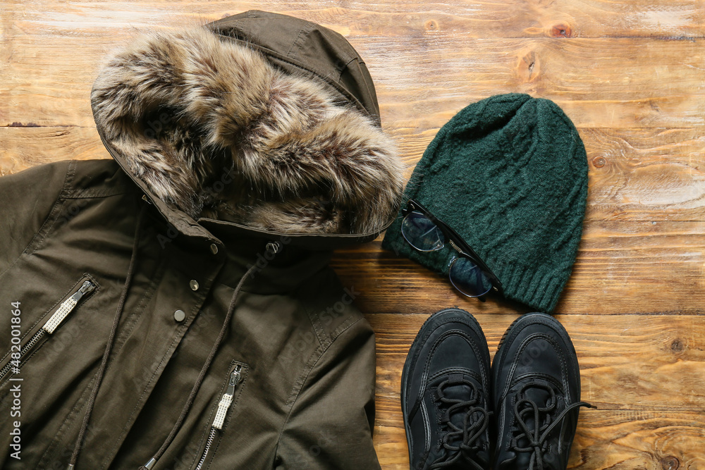 Female jacket, hat, shoes and eyeglasses on wooden background