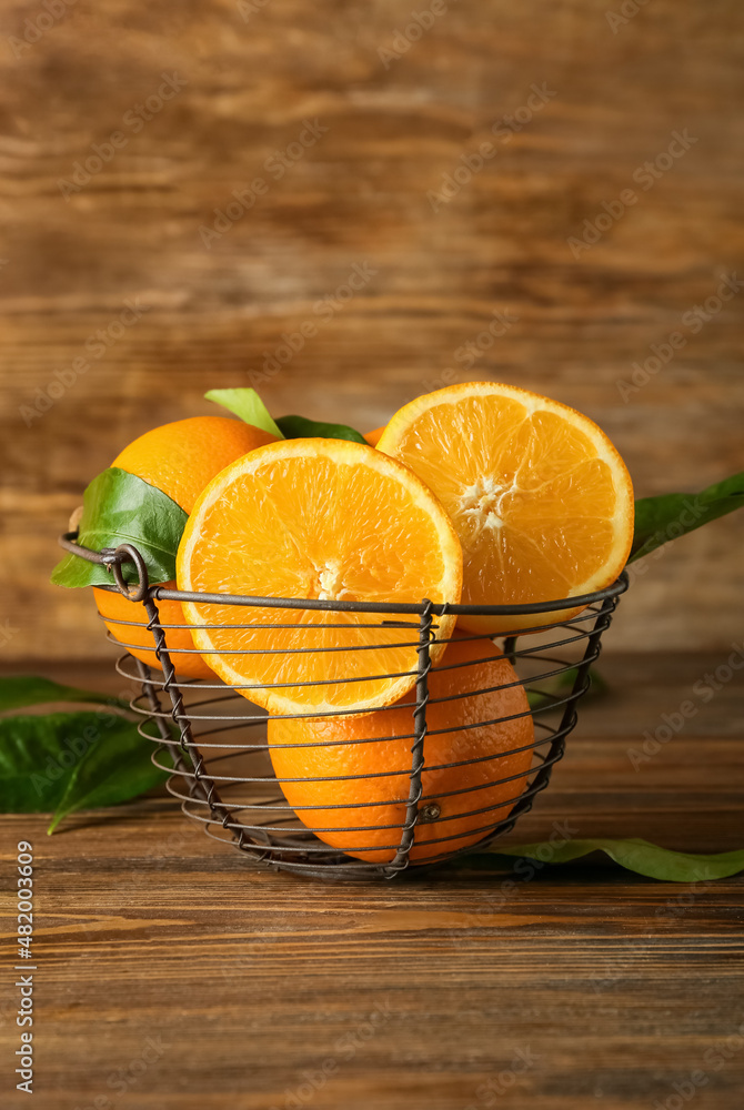 Basket with fresh juicy oranges on wooden background