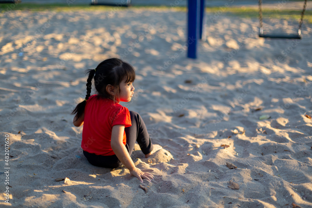 Asian child playing with sand in the playground