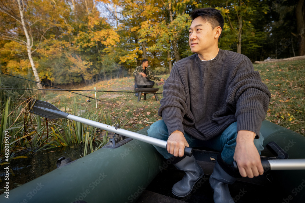 秋天早上，一名亚洲男子在湖中或河里的橡皮艇上漂浮。休息、周末和v的概念