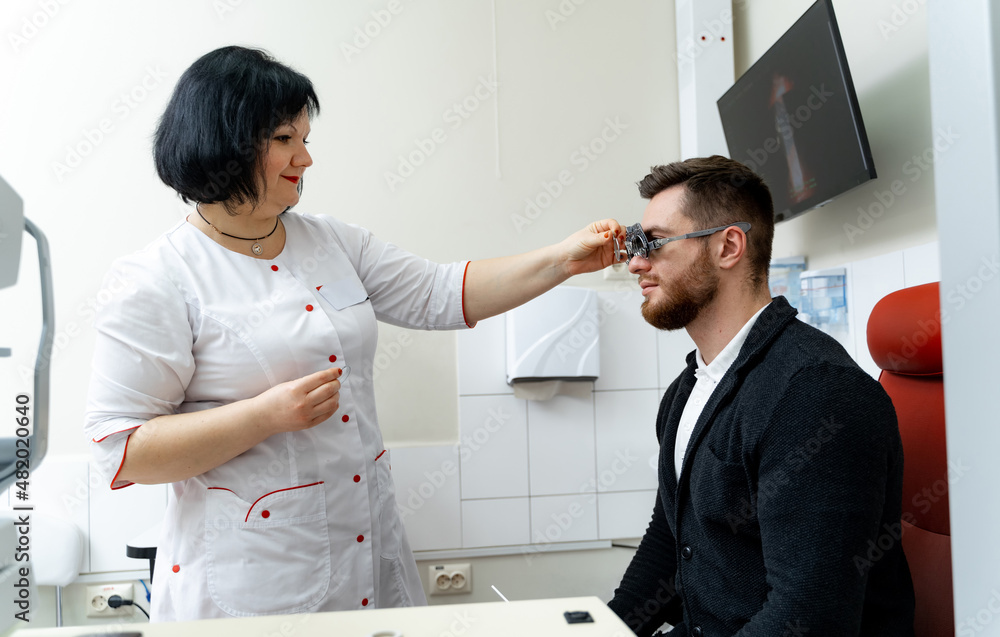 Female ophthalmologist examining mature man`s eyes. Optical specialist taking care about eyesight.