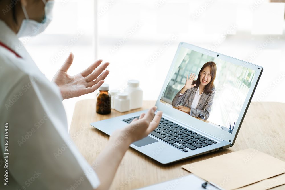 亚洲女医生使用笔记本电脑在线视频通话远程与患者交谈，开药