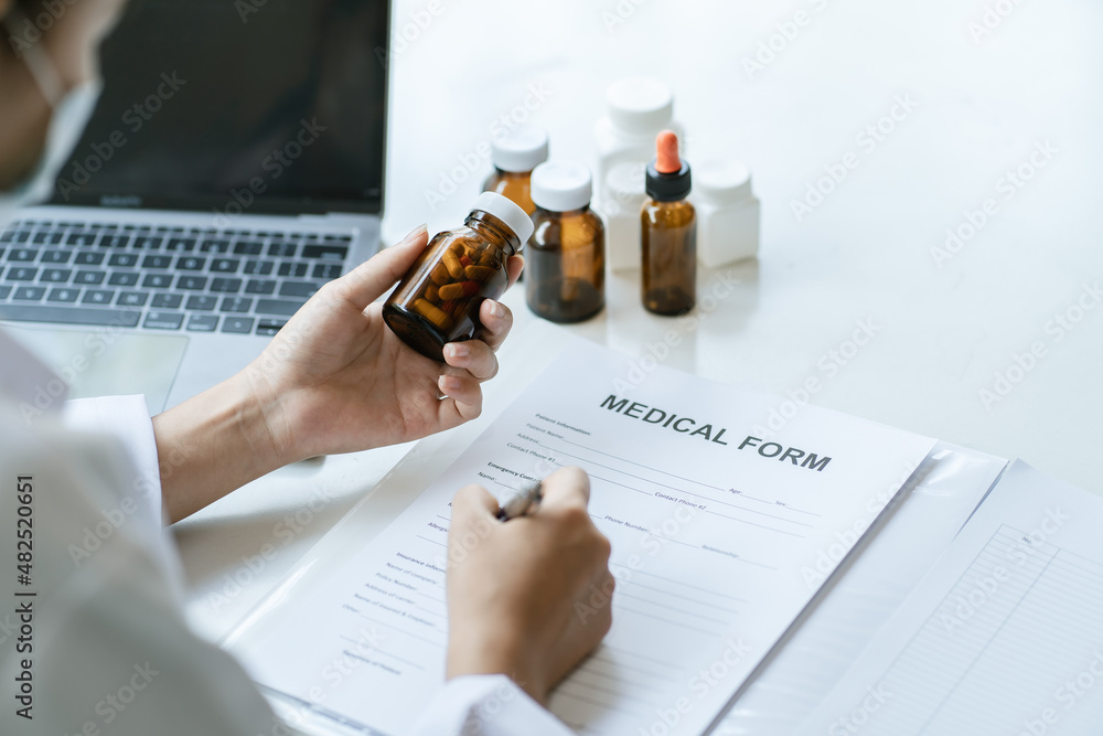 Doctor sitting at desk and writing a prescription for her patient, medical consultation concept.