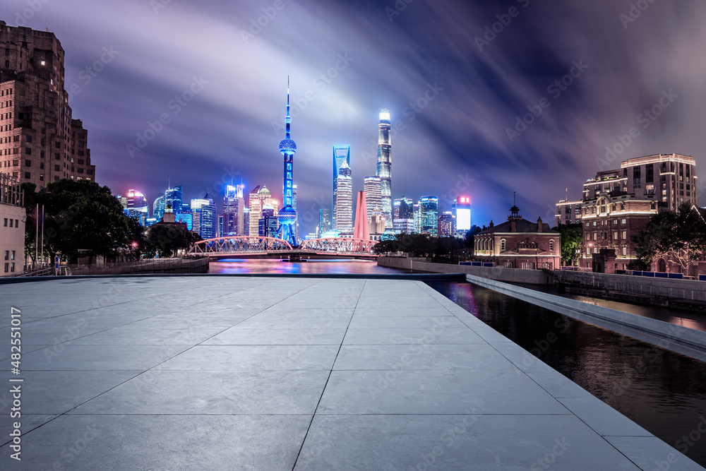 Panoramic skyline and modern commercial buildings with empty square floor in Shanghai at night, Chin