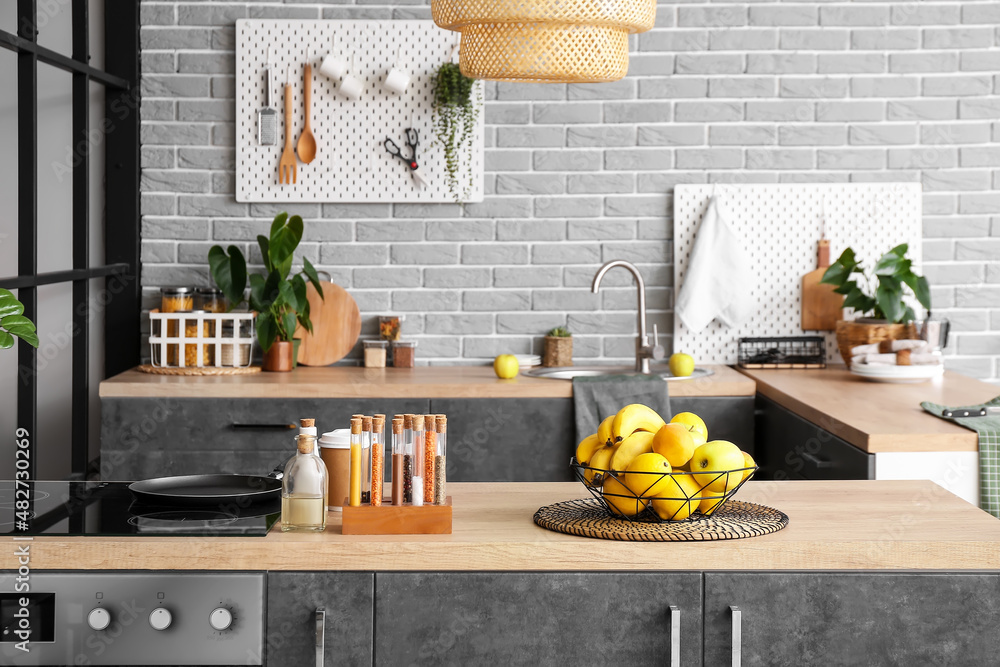 Basket with different fruits on table in kitchen interior