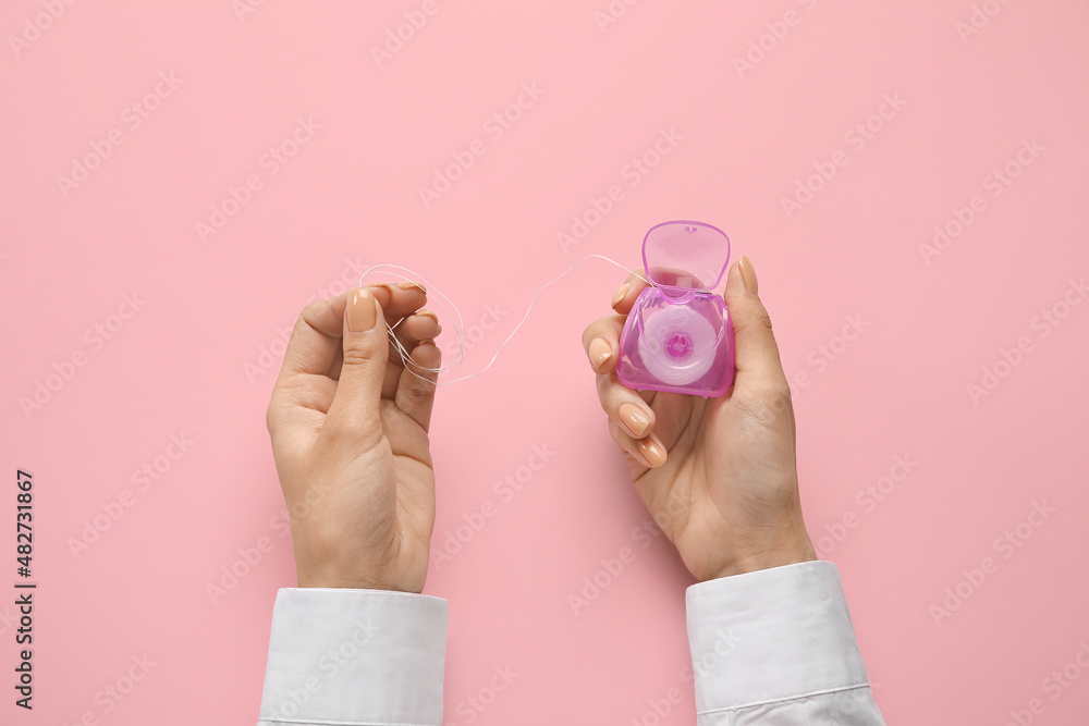 Woman with dental floss on pink background