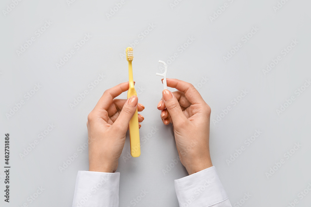 Woman with toothpick and brush on light background