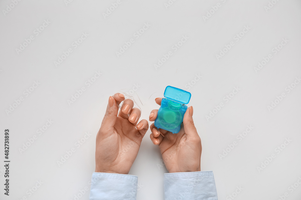 Woman with dental floss on light background