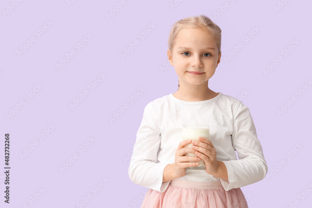 Cute little girl holding glass of milk on lilac background