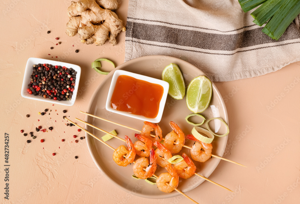 Plate with grilled shrimp skewers and sauce on beige background