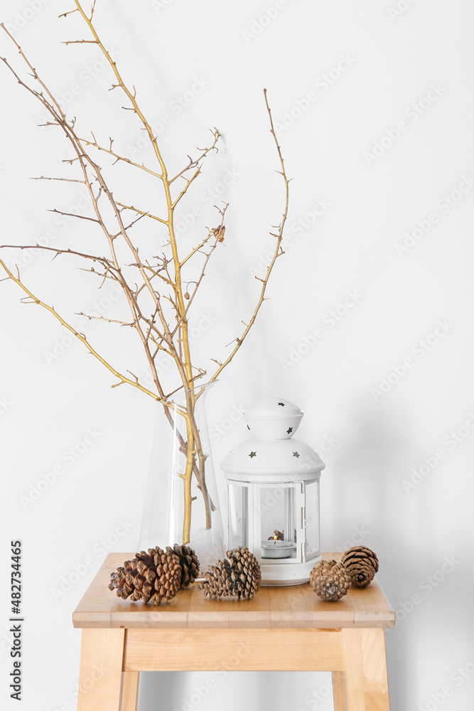 Pine cones and holder with candle on table in room