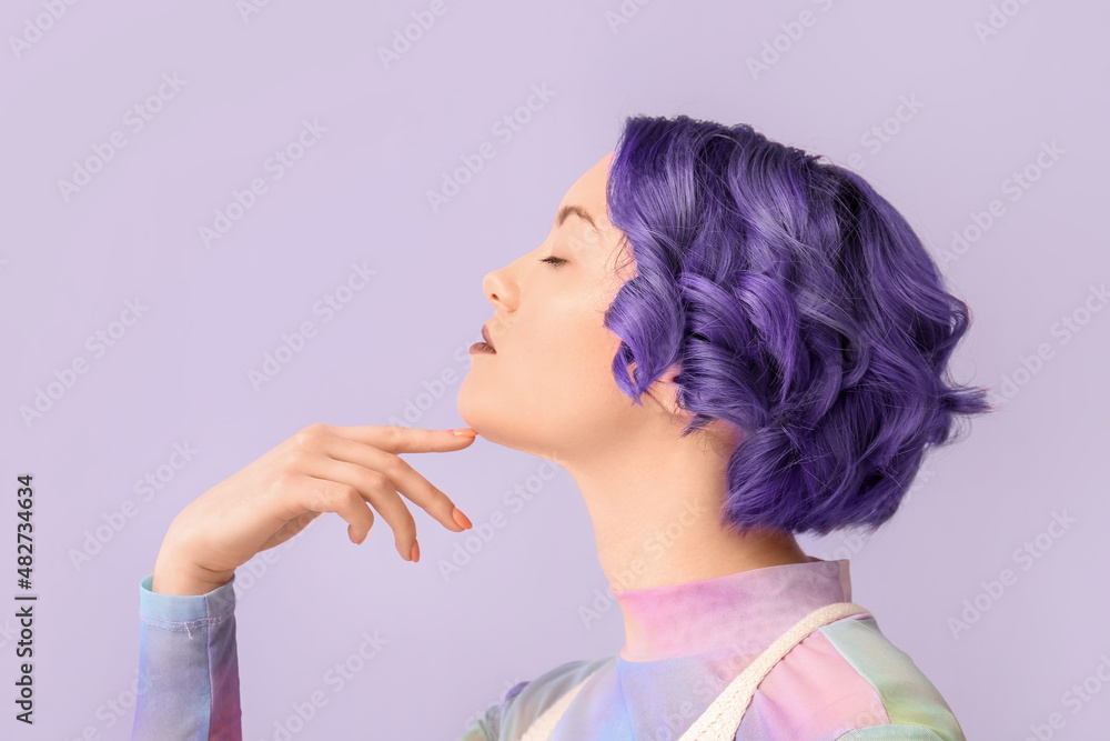 Beautiful young woman with violet hair on color background. Very Peri - color of year 2022