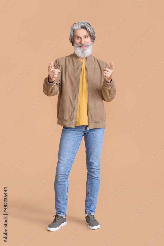 Senior man in stylish jacket on beige background