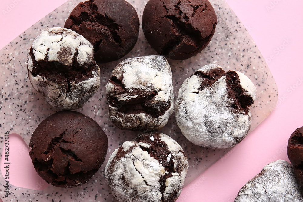 Board with tasty brownie cookies on pink background