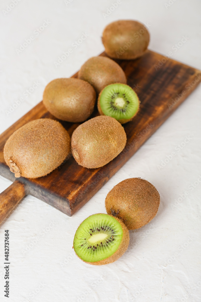 Board with fresh ripe kiwi on light background