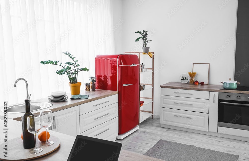 Interior of modern kitchen with refrigerator and counters