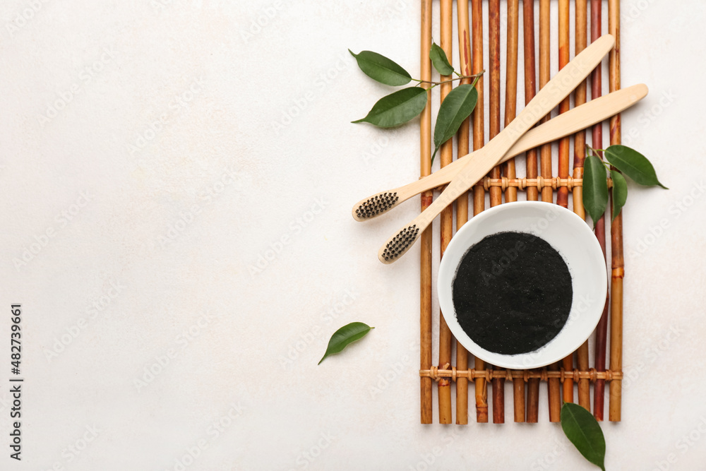 Bowl with activated charcoal tooth powder and brushes on white background