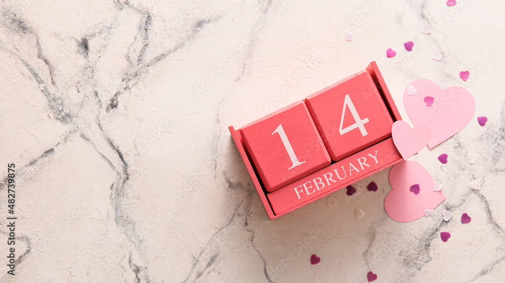 Calendar with date of Valentines Day and heart shaped confetti on white marble background