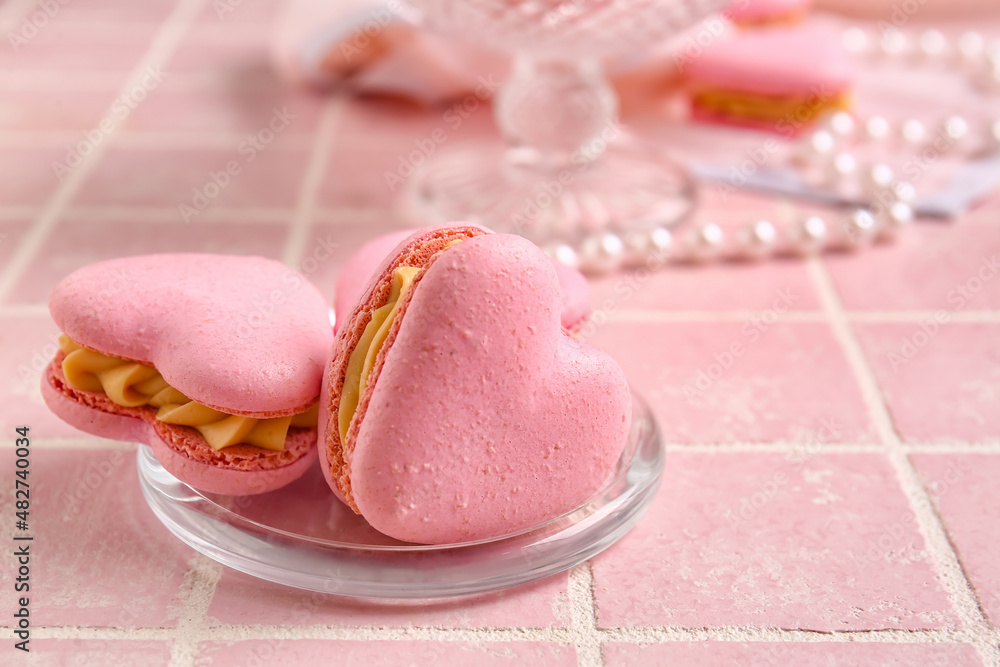 Plate with tasty heart-shaped macaroons on pink background, closeup