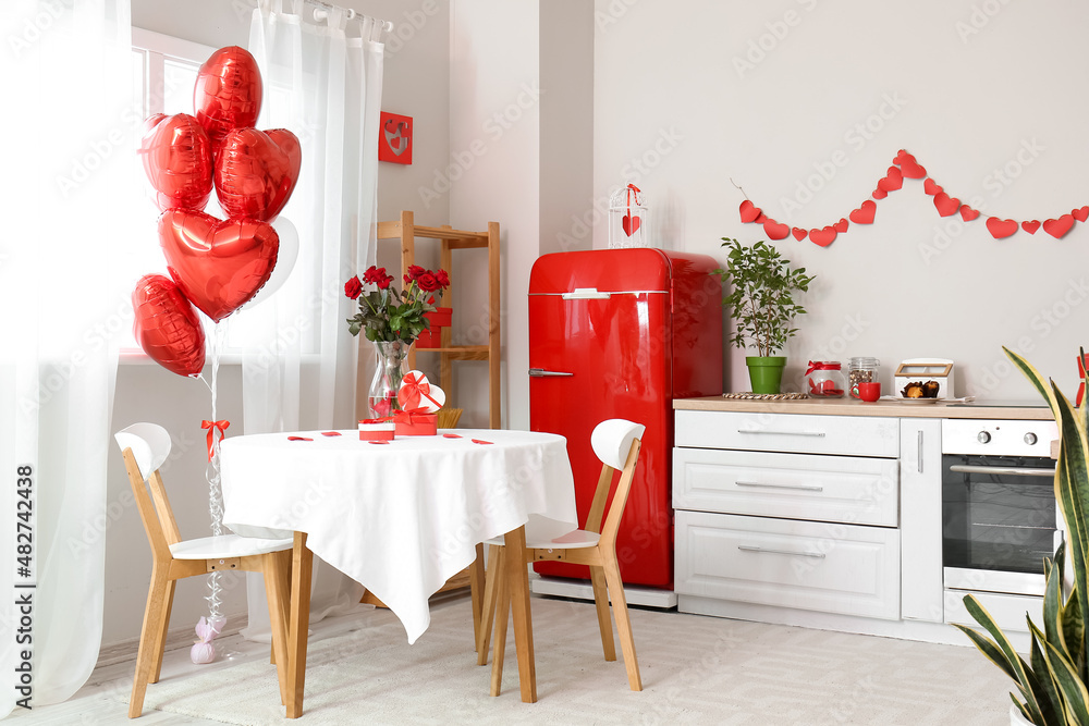 Dining table with roses and gift boxes for Valentines Day celebration in light kitchen interior