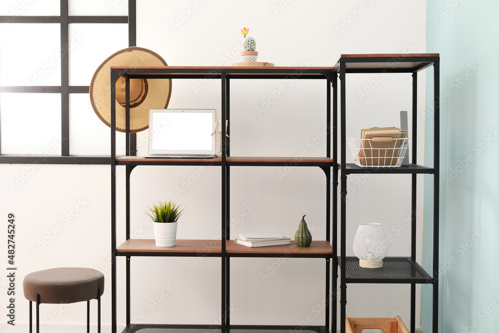 Modern shelf unit with decor and laptop in light room