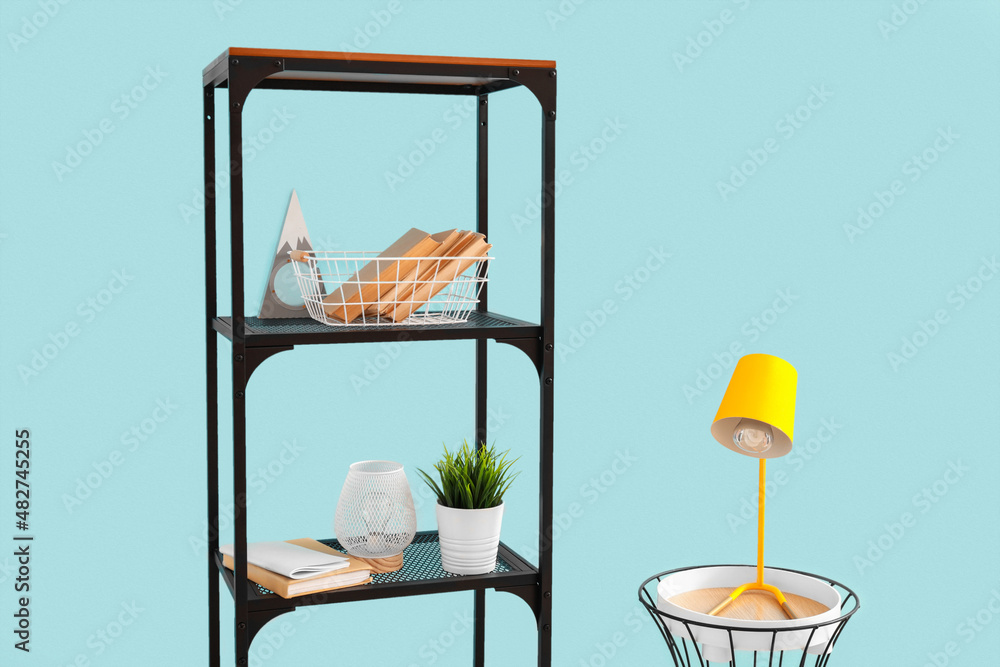 Table with lamp and shelf unit with decor near color wall