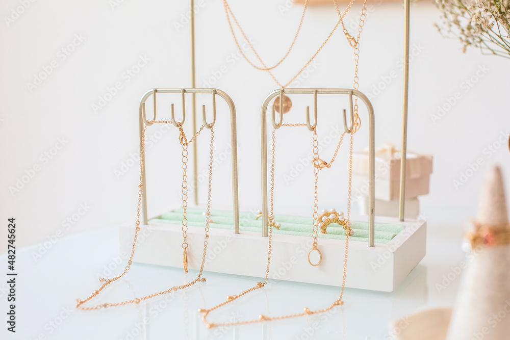 Stand with different stylish jewelry on table near light wall