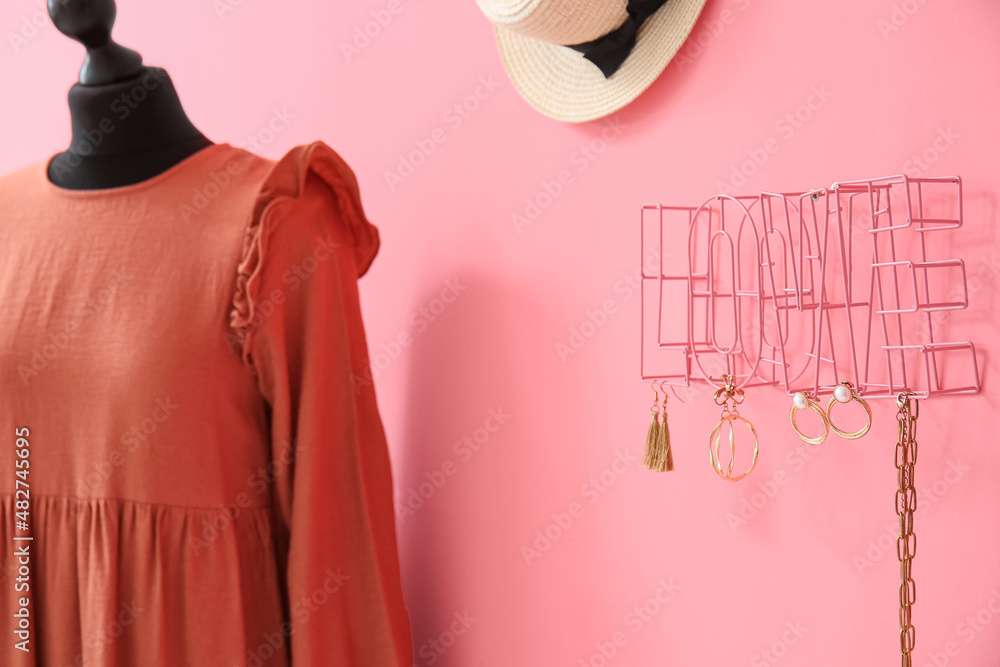 Decor in shape of word LOVE with stylish accessories and mannequin with dress near color wall