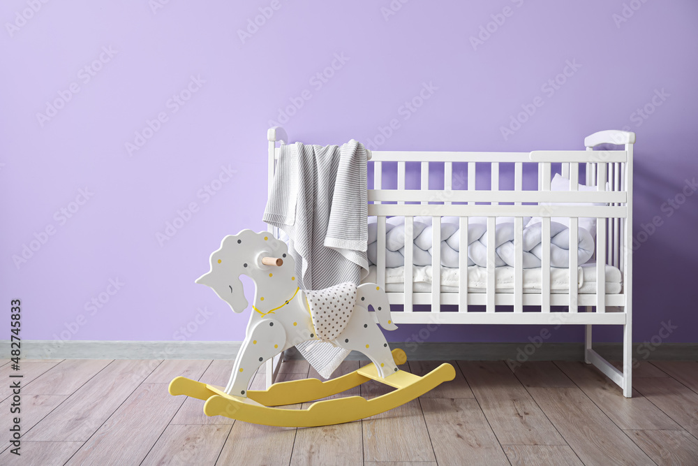 Rocking horse and crib with plaid near color wall