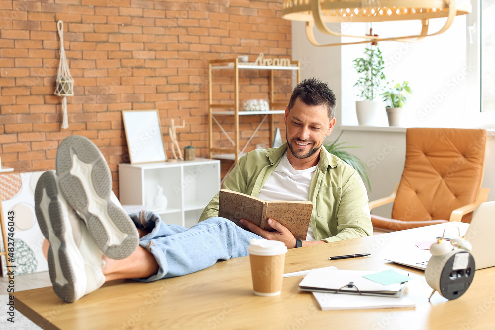 Handsome man working with notebook at table in office