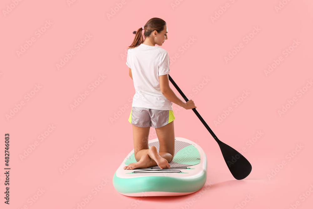 Young woman with board for sup surfing and oar on color background