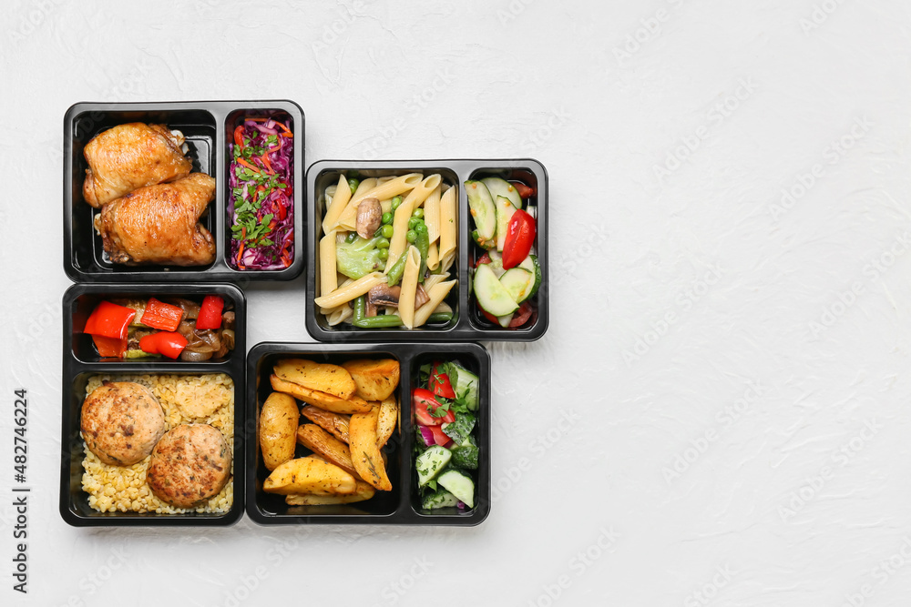 Lunch boxes with tasty meals on light background