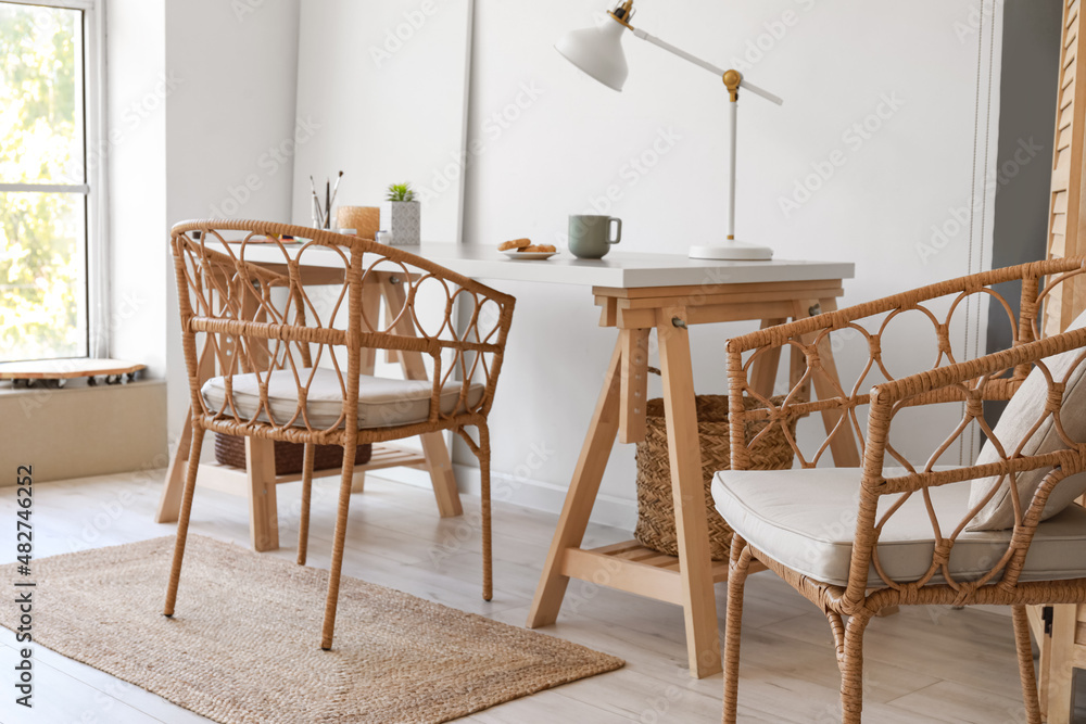 Wooden table and wicker chairs in interior of light room