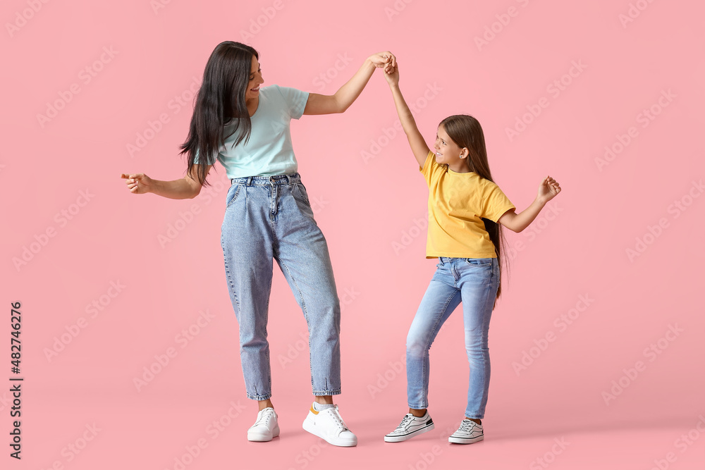 Happy dancing woman and her daughter on color background