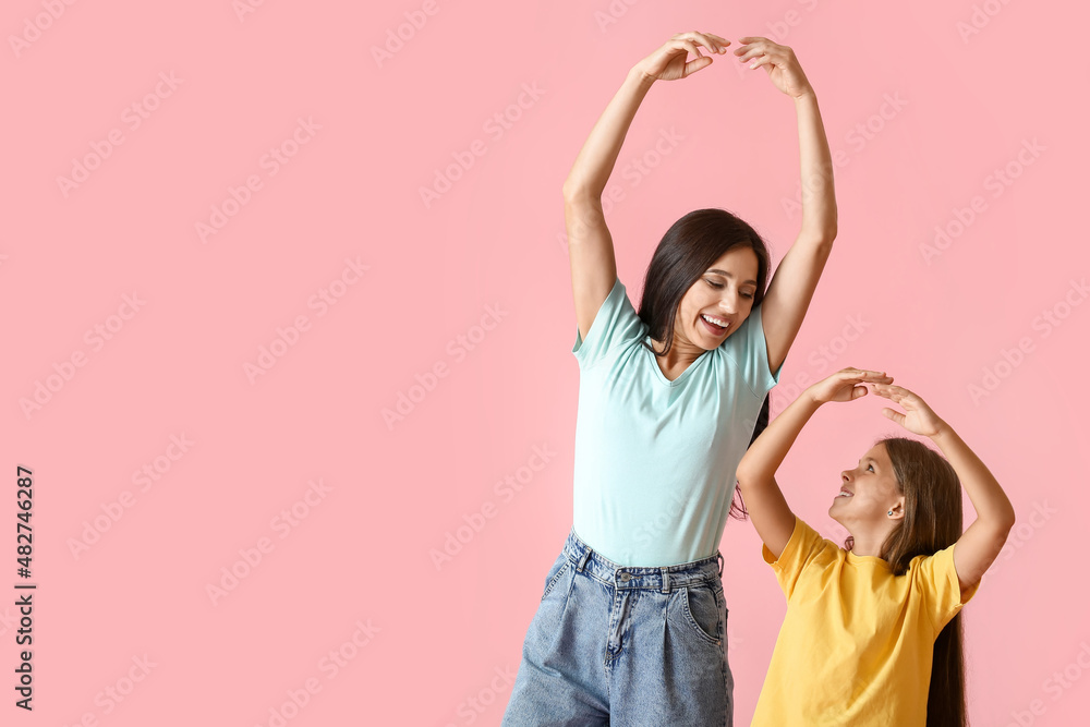 Happy dancing woman and her daughter on color background