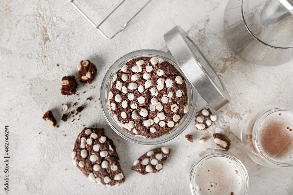 Jar of tasty cookies with white chocolate chips on light background