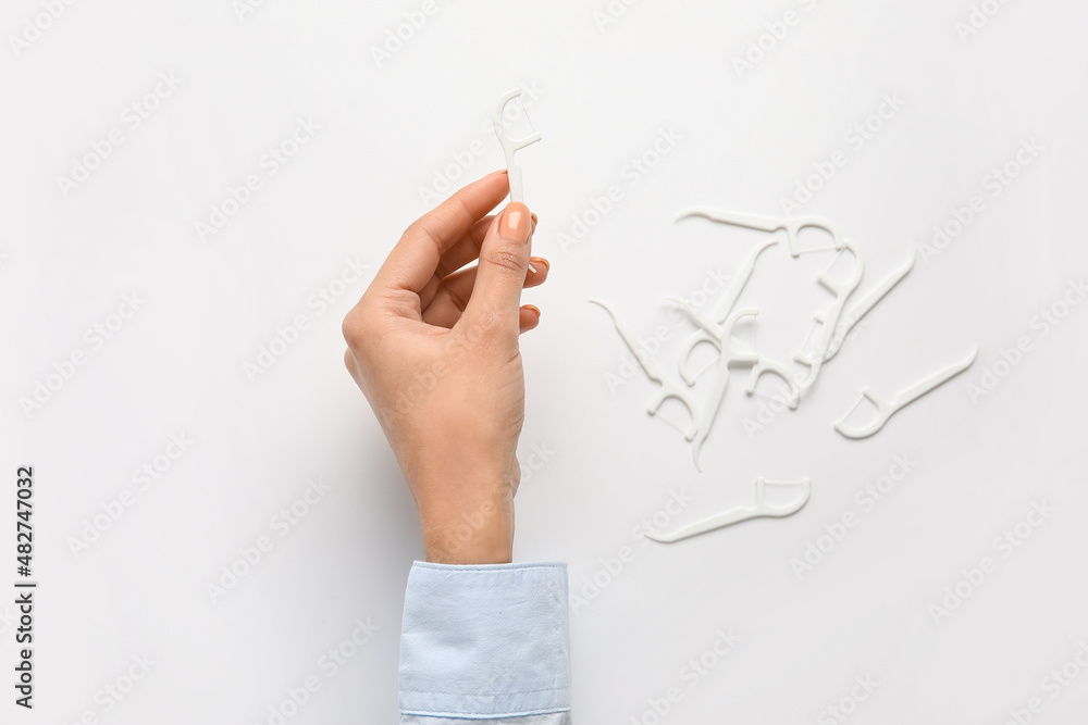 Woman with floss toothpicks on white background