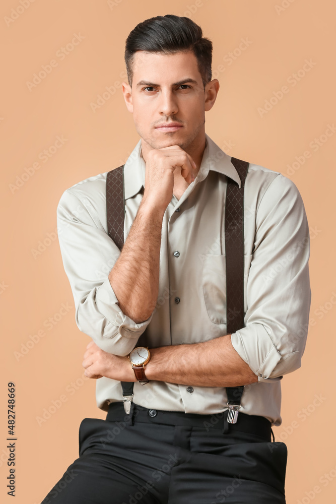 Fashionable pensive gentleman sitting on chair against color background