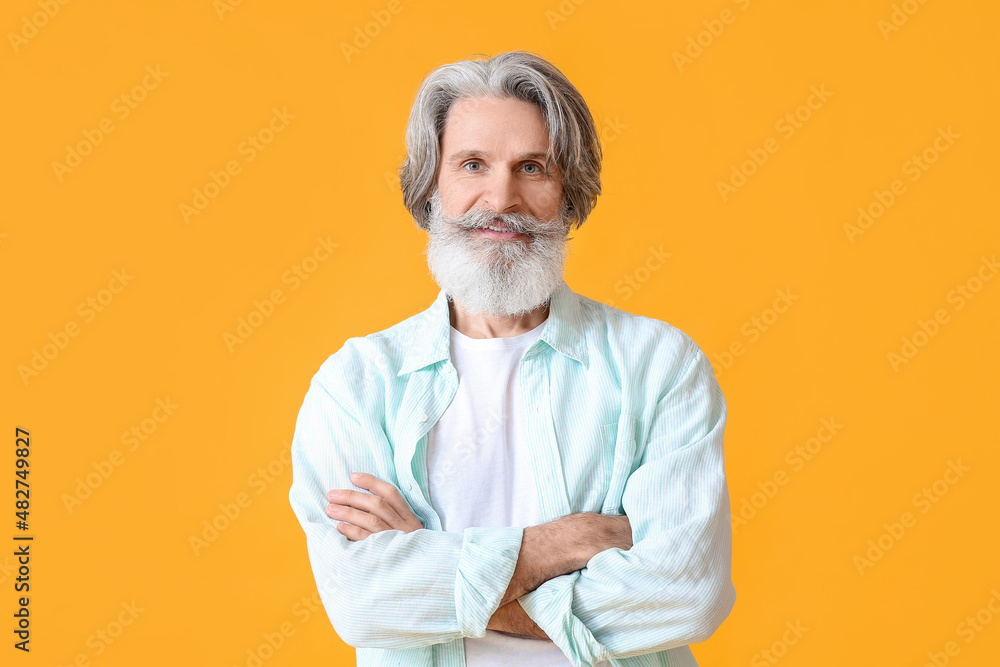 Senior man in blue shirt on yellow background