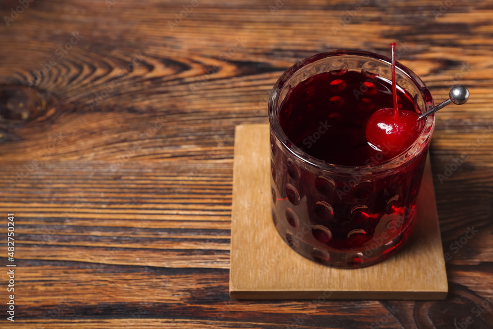 Glass of tasty Manhattan cocktail on wooden background