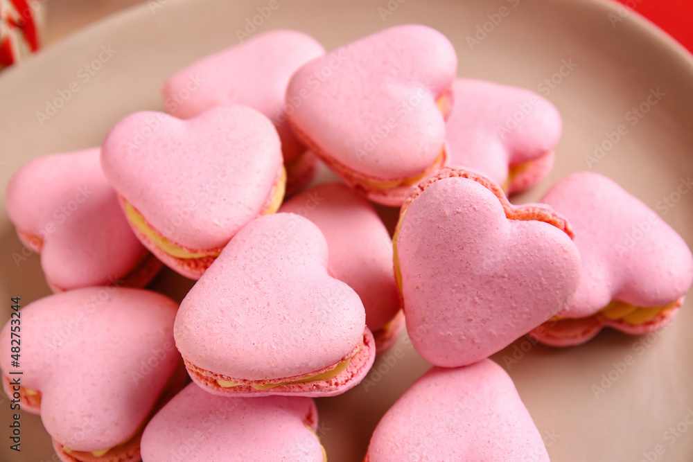 Plate with tasty heart shaped macaroons on table, closeup