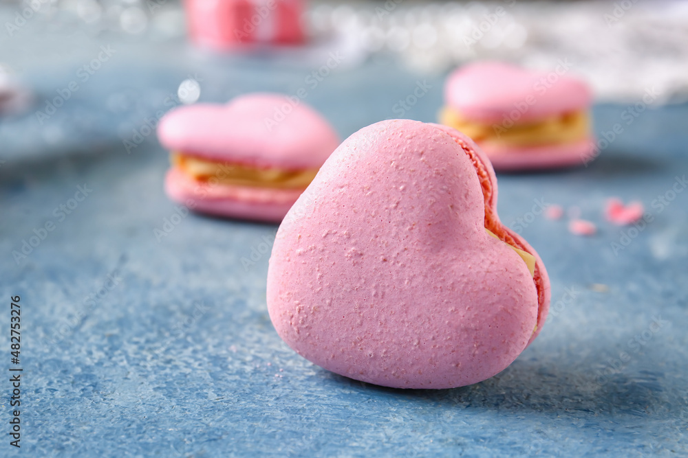 Tasty heart-shaped macaroon on blue background