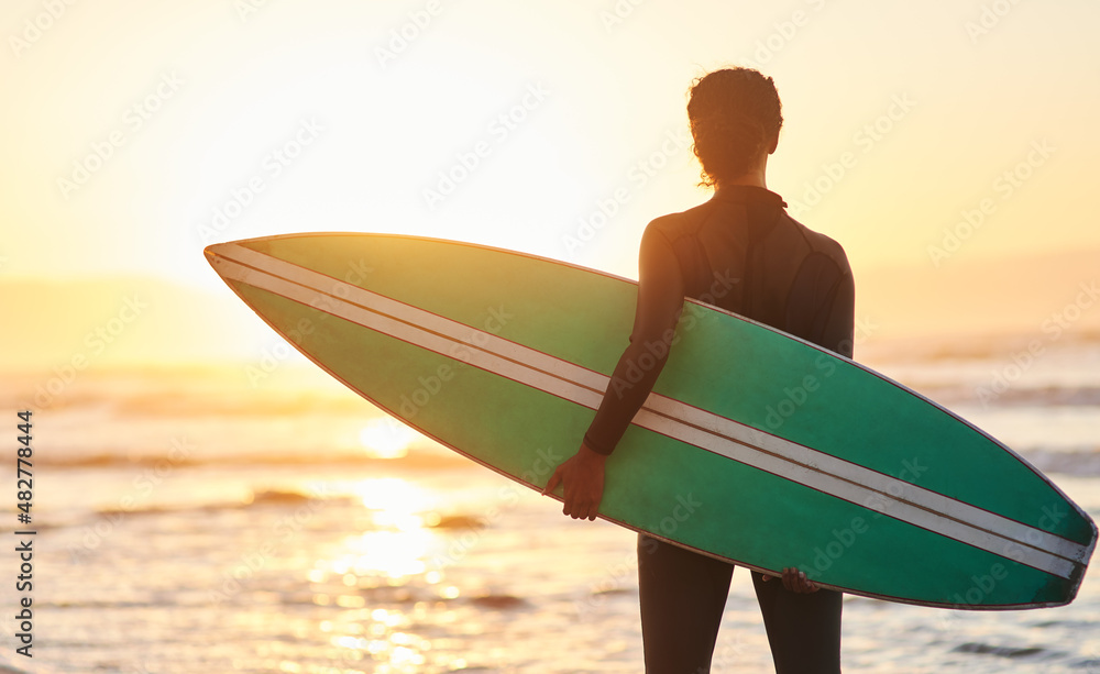 Time to ride another wave. Rearview shot of a female carrying her surfboard at the beach.