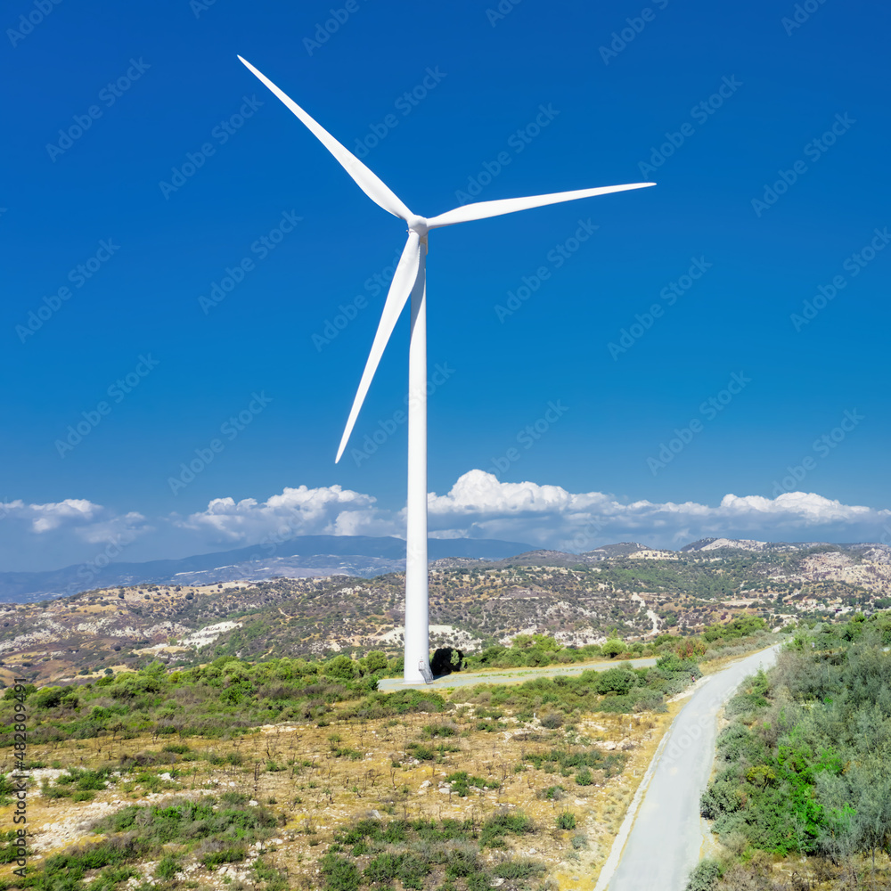 Wind turbine on top of the hill at Oreites wind farm in Cyprus against blue sky, drone view