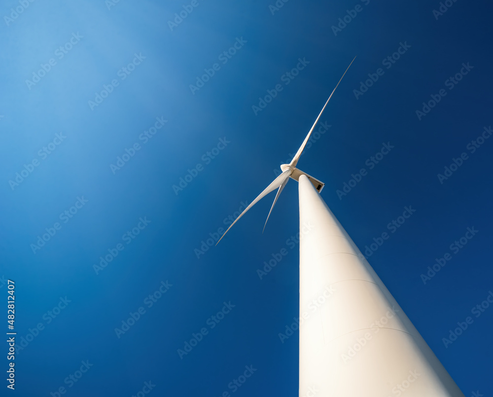 Wind generator against blue sky. Minimalistic shot, low point of view, dramatic perspective
